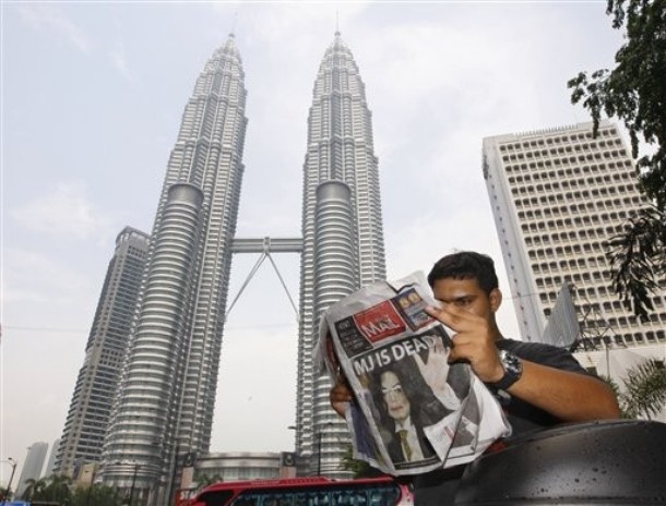 A motorcycle courier reads an afternoon paper in Kuala Lumpur, Malaysia